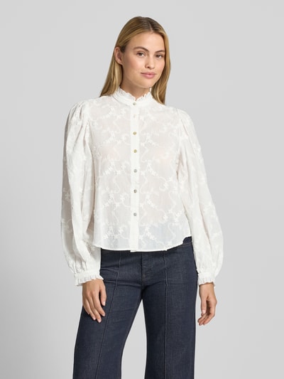 Frauenmodel trägt Bluse aus reiner Baumwolle mit Stehkragen Modell 'ROMA' von MANGO, weiße Stickerei, gerade Passform, Ganzkörperansicht von vorne.