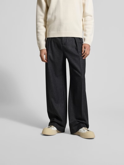 Männermodel trägt Stoffhose aus Baumwoll-Mix von Filippa K in Dunkelgrau mit Bügelfalten, Straight Fit, Eingrifftaschen, Ganzkörperansicht von vorne.