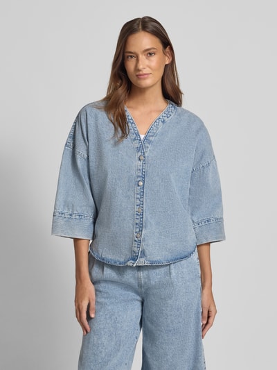 Vrouwenmodel draagt Loose fit jeansblouse uit katoen- en viscosemix Model 'VALERIA' van Vero Moda in denimlook, lichtblauw met knoopsluiting, 3/4-mouw, afgeronde rompzoom, vooraanzicht van het hele lichaam.