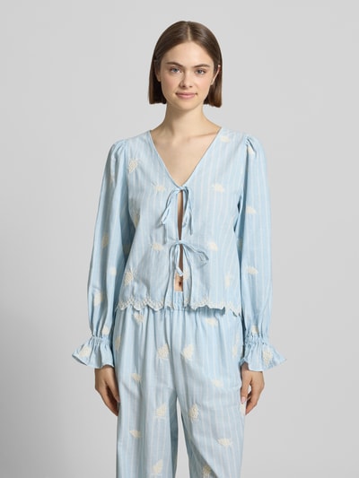 Frauenmodel trägt Bluse mit Schnürung Modell 'Ninon' von OH APRIL aus Reine Baumwolle, Straight Fit, hellblau mit weißen Streifen, V-Ausschnitt, Schnürung, Label-Stitching, Rüschenärmel, Rückenlänge bei Größe S 54 cm, Ärmellänge 61 cm, Ganzkörperansicht von vorne.