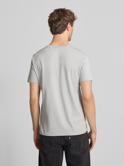 Męski model nosi T-Shirt mit Label-Print und Rundhalsausschnitt von Alpha Industries, bawełna, krój regular fit, długość tyłu 67 cm, Ganzkörperansicht Rückansicht.