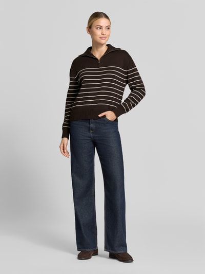 Frauenmodel trägt Regular Fit Pullover aus reiner Baumwolle von MANGO, braun mit weißen Streifen, Troyer-Kragen, Strick-Optik, Ganzkörperansicht von vorne