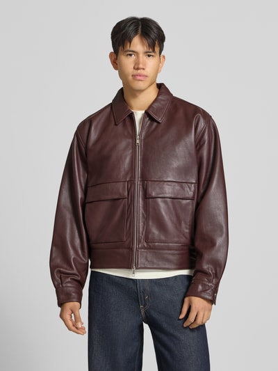 Mannelijk model draagt Lederjacke met Tweewege-Reißverschluss Modell 'DOGMA' van Edwin in bordeaux kalfsleer met platte kraag, regular fit, grote klepzakken, gladde textuur, ganzebodyaanzicht van voren. Ruglengte maat M: 66 cm, schouderbreedte: 50 cm, borstwijdte: 51 cm, mouwlengte: 68 cm.