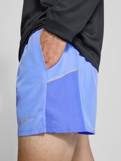 Männermodel trägt Shorts mit seitlichen Eingrifftaschen und Logo-Print von NIKE TRAINING in Hellblau, Loose Fit, Nahaufnahme Oberschenkel.