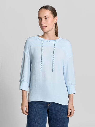 Vrouwenmodel draagt Longsleeve met Tunnelzug van Marc Cain in lichtblauw met ruches, 3/4-mouw, losse pasvorm, nahaufnahme bovenlichaam.
