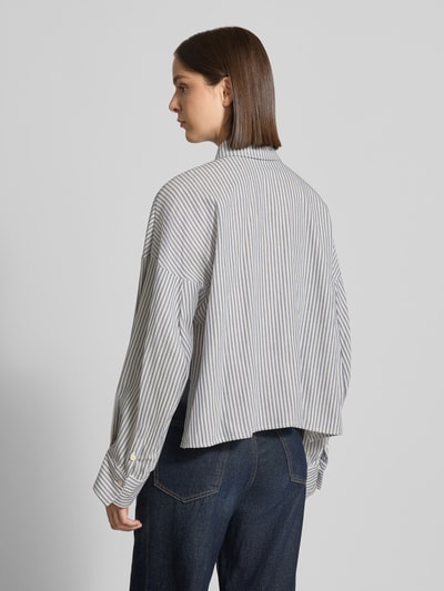 Frauenmodel trägt Relaxed Fit Hemdbluse aus reiner Baumwolle Modell 'OSHIA' von DRYKORN, feine Streifen, Hemdblusenkragen, Ganzkörperansicht Rückansicht.