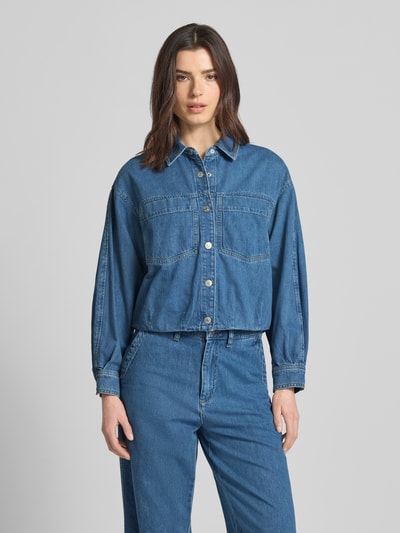 Kobiece model nosi kurtkę jeansową z bawełny o kroju relaxed fit, kołnierzyk koszulowy, kieszenie na piersi i listwa guzikowa, model 'Imke' od JOOP!, długość tyłu w rozmiarze 36: 54 cm, szerokość ramion w rozmiarze 36: 54 cm, szerokość klatki piersiowej w rozmiarze 36: 60 cm, długość rękawów w rozmiarze 36: 52 cm, niebieski denim, tekstura gładka, całkowity widok z przodu.