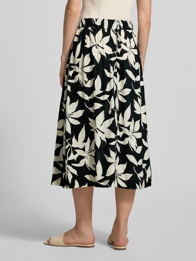 Frauenmodel trägt Relaxed Fit Ausgestellter Midi-Rock aus Viskose-Mix von s.Oliver RED LABEL mit Optik:Allover-Muster, Florales-Muster, elastischem Bundabschluss und Materialverarbeitung Popeline, Farbe Schwarz-Crème; Ganzkörperansicht Rückansicht.