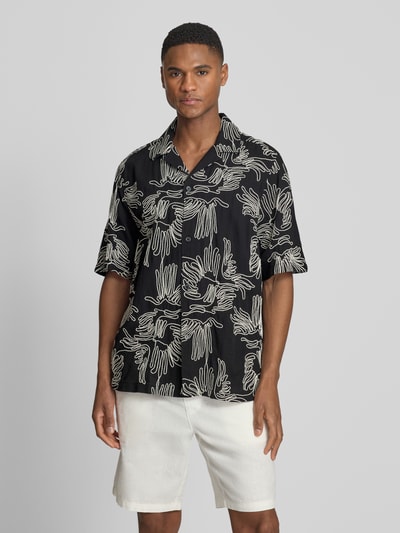 Männermodel trägt Freizeithemd mit floralem Allover-Stitching Modell 'Liam' von Les Deux, Baumwoll-Mix, Regular-Fit, Kurzärmelig, Reverskragen, durchgehende Knopfleiste, Schwarz mit beigem Muster, Ganzkörperansicht von vorne.