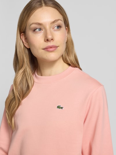 Frauenmodel trägt Relaxed Fit Sweatshirt aus reiner Baumwolle von Lacoste, Optik: Unifarben, Logo-Stitching, Materialverarbeitung: Sweat, Nahaufnahme Oberkörper.