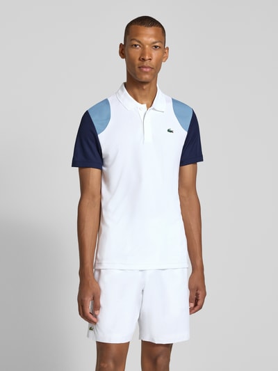 Männermodel trägt Regular Fit Sport-T-Shirt im Colorblock-Design von Lacoste, weiß mit blauen Ärmeln, Ganzkörperansicht von vorne, Herren Sport-T-Shirt von Lacoste Sport.