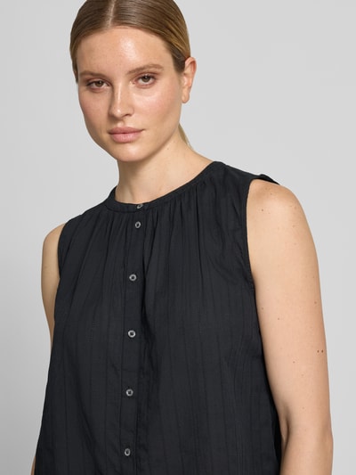 Vrouwenmodel draagt Relaxed Fit Bluse aus reiner Baumwolle van Marc O'Polo in effen kleuren met ajourwerk, mouwloos, ronde hals, knoopsluiting. Nahaufnahme bovenlichaam.