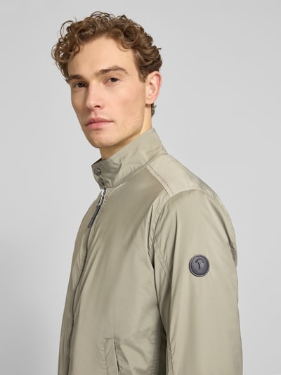 Männermodel trägt Jacke mit Stehkragen Modell 'Vicente' von JOOP! Collection in Beige mit Reißverschluss und Eingrifftaschen, Nahaufnahme Oberkörper. Herren Jacke, Regular-Fit, Rückenlänge 66 cm, Schulterbreite 46 cm, Brustweite 52 cm, Ärmellänge 67 cm.