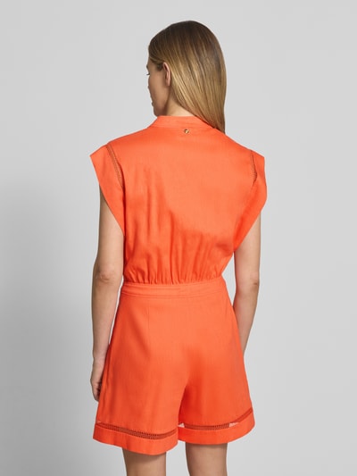 Frauenmodel trägt Jumpsuit aus Leinen-Mix mit Loch-Stickerei von Marc Cain in kräftigem Orange, strukturierter Stoff, taillierte Passform, Ganzkörperansicht Rückansicht.