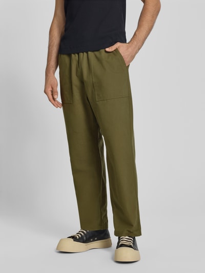 Männermodel trägt Straight Fit Stoffhose aus Baumwolle von MAISON KITSUNÉ in Olivgrün mit elastischem Bund, Ganzkörperansicht von vorne.