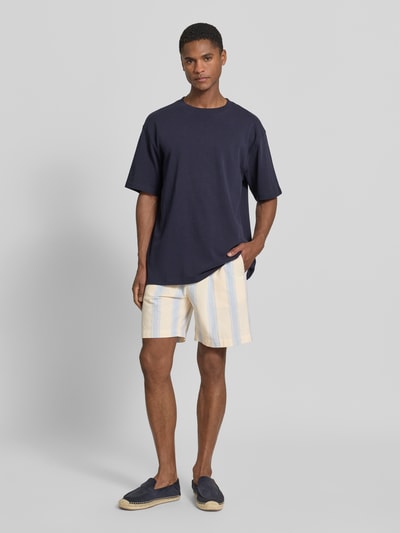 Männermodel trägt Regular Fit Shorts aus reiner Baumwolle von Armedangels, Optik:Allover-Muster, gestreift, Twill, Ganzkörperansicht von vorne.