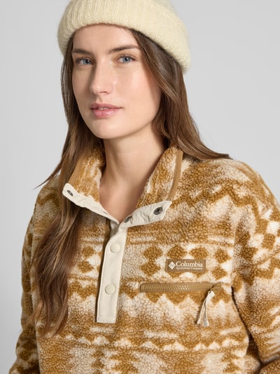 Modelka nosi Regular Fit Pullover mit Logo-Patch Modell 'Helvetia' od Columbia, beżowo-brązowy wzór, kieszeń na piersi, krój regular fit, zbliżenie na górną część ciała