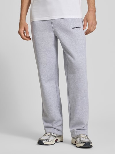 Männermodel trägt Loose Fit Sweatpants aus Baumwoll-Mix mit Label-Detail von PEGADOR in Hellgrau, elastischer Bund, Eingrifftaschen, Nahaufnahme Oberkörper.