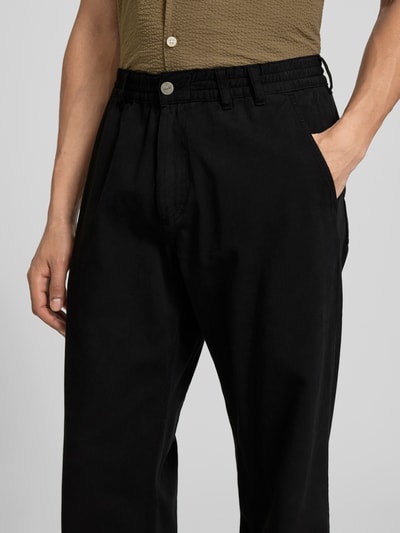Männermodel trägt Straight Fit Jeans mit elastischem Bund von Forét in Schwarz, reine Baumwolle, Nahaufnahme Oberkörper.