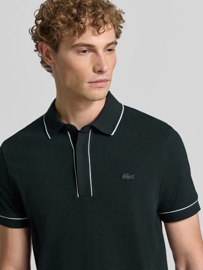 Männermodel trägt Regular Fit Poloshirt aus Baumwoll-Mix Modell 'CHEMISE' von Lacoste, dunkelgrün mit weißen Akzenten, Nahaufnahme Oberkörper, Herren Poloshirt von Lacoste.