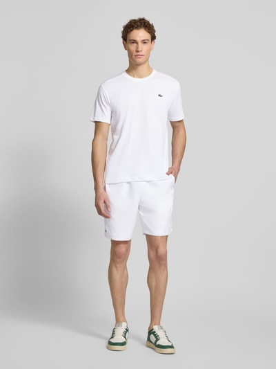 Mannenmodel draagt Regular Fit T-Shirt aus Baumwoll-Mix van Lacoste Sport, wit, unicolor, rond hals, korte mouwen, sneldrogend, logo-applicatie, katoenmix. Volledige lichaamsvooraanzicht.