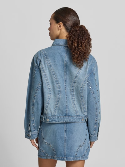 Frauenmodel trägt Jeansjacke mit Nieten und Eingrifftaschen Modell 'CLIO' von YAS aus Reine Baumwolle im Relaxed-Fit, Ganzkörperansicht Rückansicht. Rückenlänge bei Größe 36: 53 cm, Schulterbreite: 53 cm, Brustweite: 55 cm, Ärmellänge: 55 cm. Denim in Blau mit sichtbaren Nähten und strukturierter Textur.