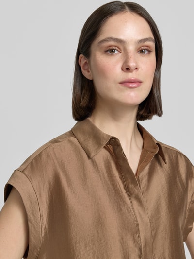 Frauenmodel trägt Regular Fit Bluse aus Lyocell-Mix Modell 'Zamin' von Someday mit Hemdblusenkragen und Kappärmel, Nahaufnahme Oberkörper. Rückenlänge bei Größe 36: 62 cm, Ärmellänge bei Größe 36: 12 cm, glänzende, glatte Textur, brauner Farbton.