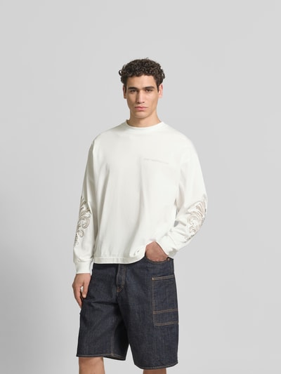 Männermodel trägt Oversized Sweatshirt aus Baumwolle von Don’t Waste Culture in Weiß mit Florale-Stickereien, elastische Abschlüsse, Ganzkörperansicht von vorne.