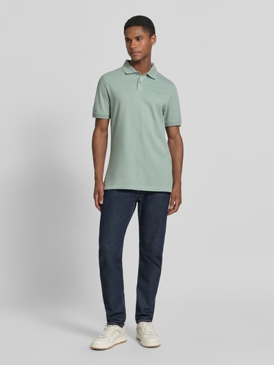 Męski model nosi Regular Fit Poloshirt aus reiner Baumwolle von s.Oliver RED LABEL, efekt: jednolity kolor, krój regular fit, wyhaftowane logo, kołnierzyk polo, dekolt w serek, listwa guzikowa, krótki rękaw, zakończenie rękawów prążkowane, wykończenie z rozcięciami po bokach, wykończenie materiału: pika, materiał: bawełna, całopostaciowy widok z przodu.