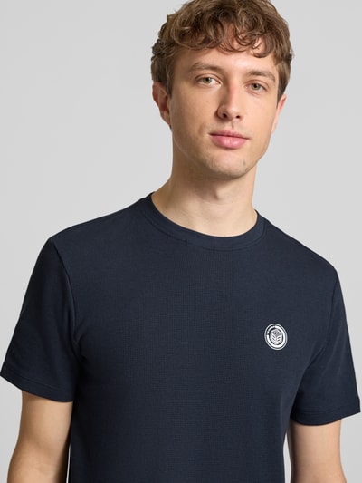 Mężczyznamodel nosi Regular Fit T-Shirt mit Strukturmuster Modell 'Kaito' od Blend, czysta bawełna, krój regular fit, okrągły dekolt, detal z logo, kolor granatowy, fakturowany materiał, długość tyłu w rozmiarze M: 71 cm, zbliżenie na górną część tułowia.