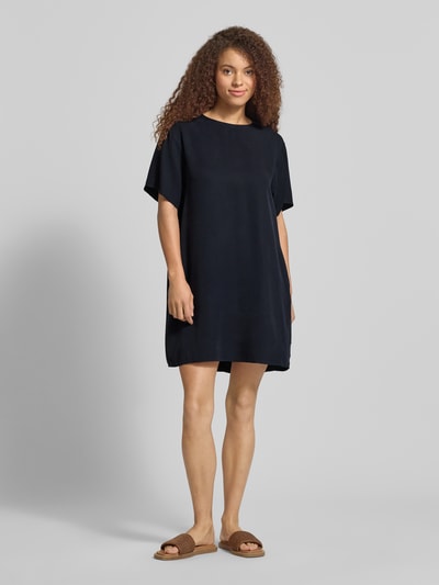 Modelka nosi Figurumspielendes Freizeitkleid aus Lyocell od Marc O'Polo Denim, efekt: jednolity kolor, krój podkreślający figurę, długość mini, okrągły dekolt, naszywka z logo, zapięcie na haftki, krótki rękaw, wykończenie materiału: pika, materiał: lyocell; całkowity widok z przodu.
