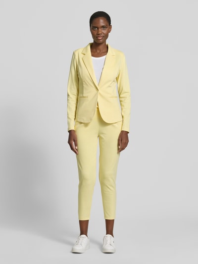 Frauenmodel trägt Regular Fit Blazer mit Paspeltaschen Modell 'KATE' von ICHI in Gelb, Material-Mix mit Viskose-Anteil, Ganzkörperansicht von vorne. Rückenlänge bei Größe S: 60 cm, Brustweite bei Größe S: 38 cm, Ärmellänge bei Größe S: 62 cm, Reverskragen, Knopfverschluss.