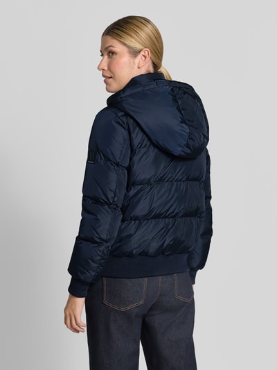 Frauenmodel trägt Steppjacke mit Daunen-Feder-Füllung von Armani Exchange in Dunkelblau mit Kapuze, elastischem Material-Mix, Rückenansicht, Ganzkörperansicht Rückansicht.