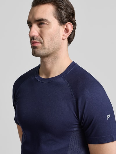 Mężczyzna nosi Regular Fit T-Shirt mit Logo-Print od Fabletics, granatowy, krótki rękaw, okrągły dekolt, krój regular fit, widok z przodu w półzbliżeniu.
