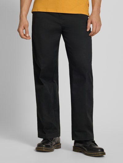 Männermodel trägt Loose Straight Fit Hose mit Bügelfalten von Dickies aus schwarzem Material-Mix mit Eingrifftaschen, Nahaufnahme Unterkörper.