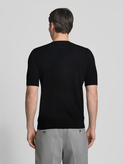 Männermodel trägt Slim Fit T-Shirt aus Strick von HUGO in Schwarz, kurzarm, Rundhals, Label Stitching, Ganzkörperansicht Rückansicht.