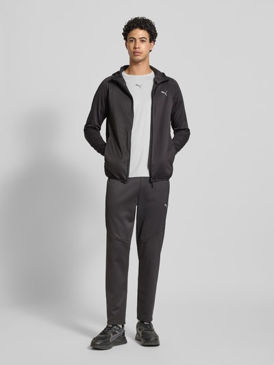 Männermodel trägt Sweatpants mit elastischem Bund von PUMA PERFORMANCE in Dunkelgrau mit Label-Print, Ganzkörperansicht von vorne.