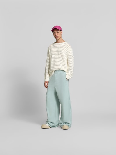 Männermodel trägt Relaxed Fit Pullover in Strick-Optik von MM6 Maison Margiela aus reiner Baumwolle, weiße Streifen, Ganzkörperansicht von vorne.