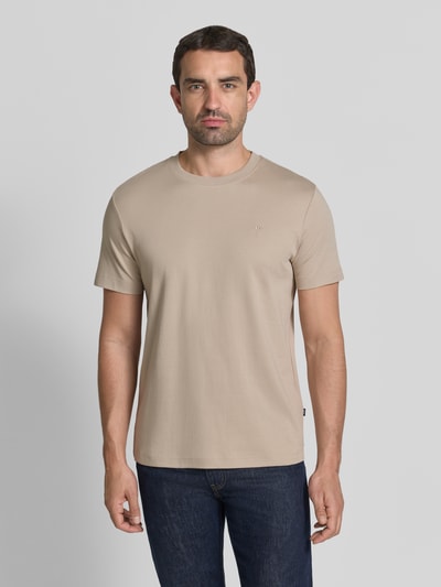 Męski model nosi T-Shirt mit Rundhalsausschnitt und Logo-Stitching von JOOP! aus bawełny, krój regular fit, okrągły dekolt, beżowy, wyhaftowane logo, kolekcja, Długość tyłu w rozmiarze M: 68 cm, widok całej sylwetki z przodu.