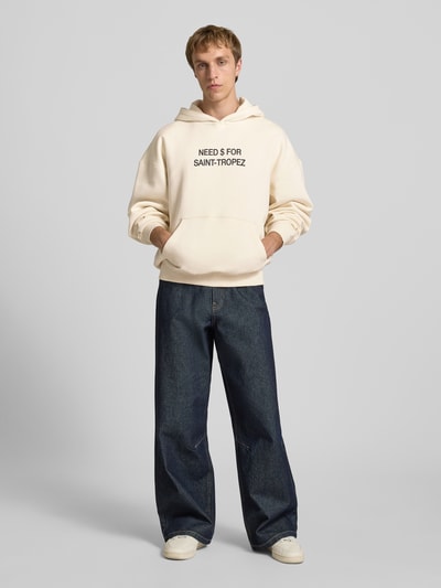 Männermodel trägt Oversized Hoodie aus Baumwoll-Mix Modell 'LEROY' von Only & Sons, unifarben, Statement Print, Kängurutasche, Sweattextur, Ganzkörperansicht von vorne.