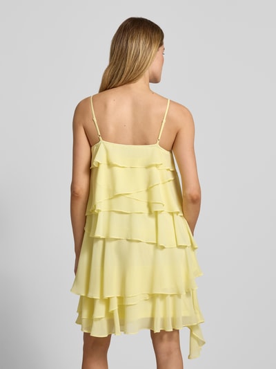 Vrouwenmodel draagt Fließendes Cocktailkleid mit Volants Modell 'ALADYN' van Vero Moda, effen geel, vloeiende fit, mini, vierkante hals, sierbloem, verstelbare spaghettibandjes, rugaanzicht volledig lichaam