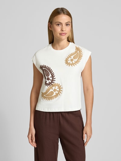 Frauenmodel trägt T-Shirt mit Rundhalsausschnitt und Stitchings von Stefanel aus reiner Baumwolle, Regular Fit, weiß mit Paisley-Muster, Nahaufnahme Oberkörper.