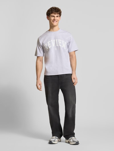 Männermodel trägt T-Shirt mit Label-Print und Rundhalsausschnitt von REVIEW in Hellgrau, Regular Fit, reine Baumwolle, Ganzkörperansicht von vorne.