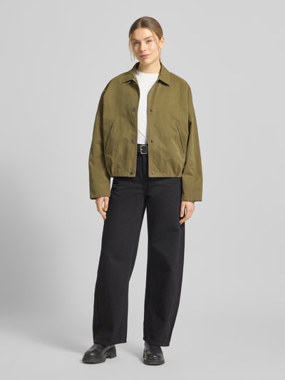 Frauenmodel trägt Blouson aus reiner Baumwolle von WHITE LABEL in Oliv, lockere Passform, Umlegekragen, durchgehende Knopfleiste, Eingrifftaschen, Rückenlänge 62 cm, Schulterbreite 40 cm, Brustweite 64 cm, Ärmellänge 65 cm, Ganzkörperansicht von vorne.