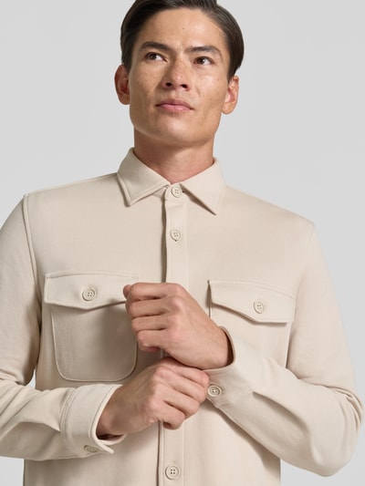 Männermodel trägt Overshirt mit Knopfleiste von MCNEAL in Beige, Material-Mix mit Baumwoll-Anteil, Brusttaschen, Nahaufnahme Oberkörper.