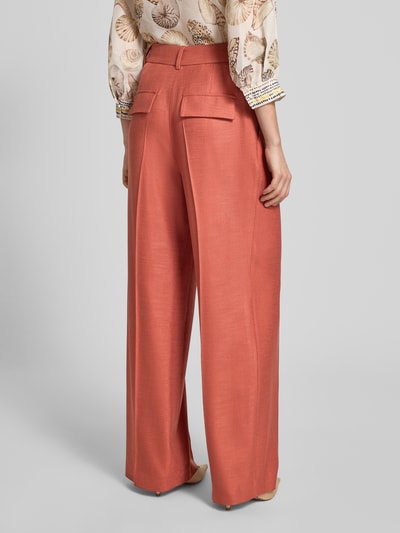 Frauenmodel trägt Wide Fit Hose aus Viskose-Elasthan-Mix von Marc Cain in Orange mit Bügelfalten, High-Waist, Ganzkörperansicht Rückansicht.
