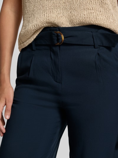 Frauenmodel trägt Culotte aus Viskose mit Gürtel von Christian Berg Woman in Dunkelblau mit Biesen und französischen Eingrifftaschen, Nahaufnahme Oberkörper.