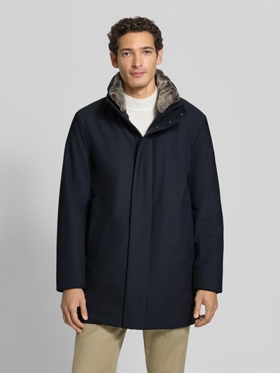 Männermodel trägt dunkelblauen Regular Fit Parka mit abnehmbarem Kunstfellbesatz Modell 'Flex' von Strellson, Herren Parka, Ganzkörperansicht von vorne.