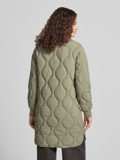 Frauenmodel trägt Steppjacke mit Stehkragen und Eingrifftaschen von Superdry in olivgrün mit sichtbarer Steppung, Ganzkörperansicht Rückansicht. Regular Fit, Reißverschluss, Länge 91 cm, Schulterbreite 38 cm, Brustweite 50 cm, Ärmellänge 63 cm.
