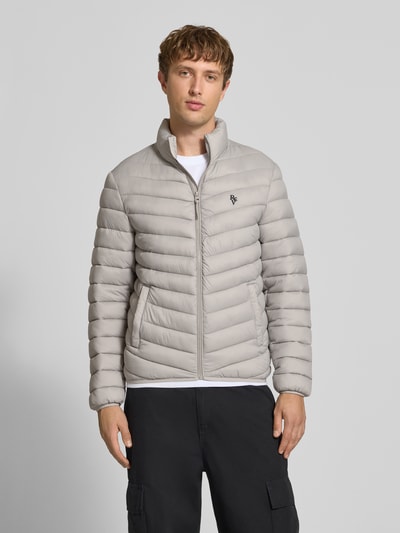 Männermodel trägt Regular Fit Steppjacke mit Logo-Stickerei von REVIEW in Stepp-Optik, Hellgrau, Reißverschluss, Ganzkörperansicht von vorne.